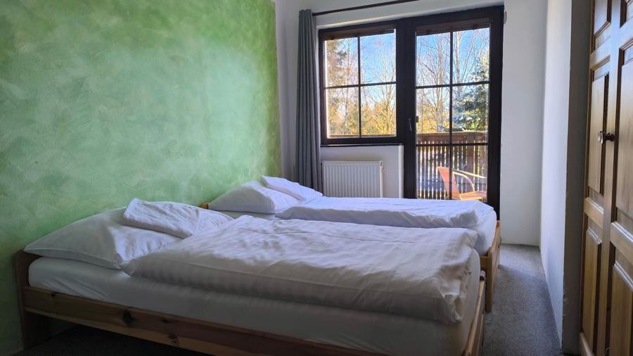 Ložnice se zelenou stěnou a balkonovými dveřmi